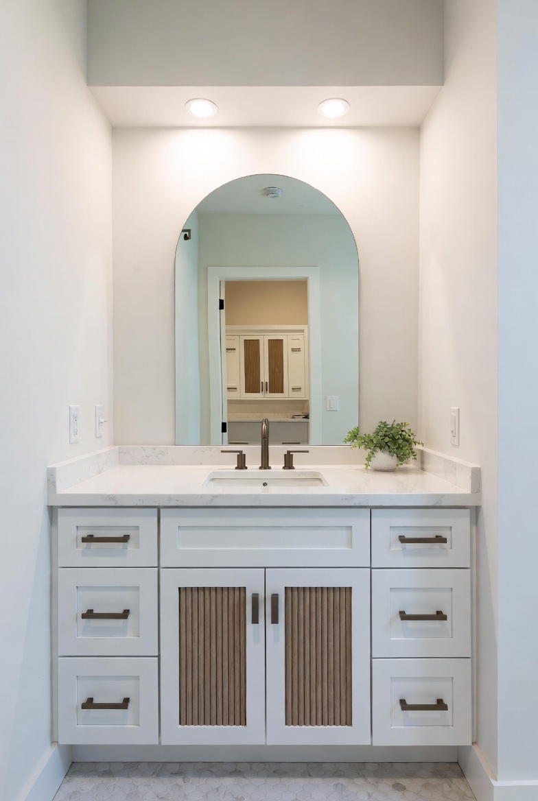 White bathroom vanity with vertical slat door inserts and a stone countertop